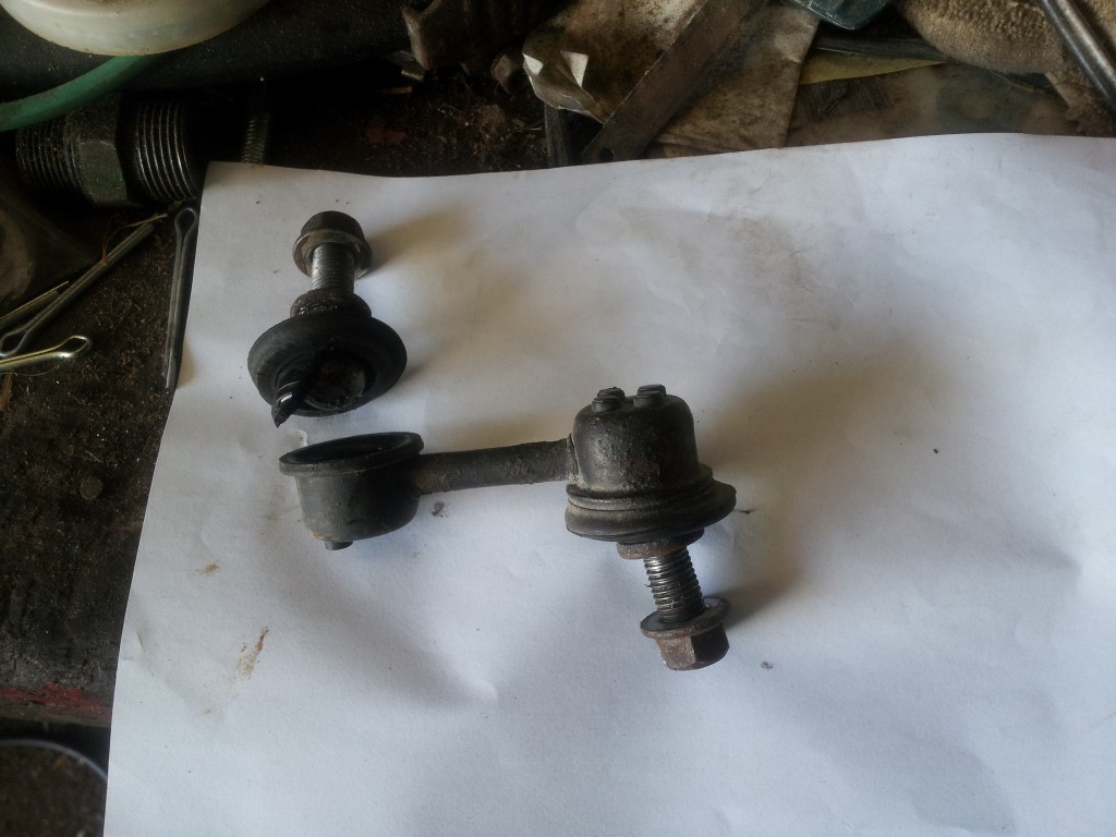 Worn sway bar end link and hardware on a sheet of paper